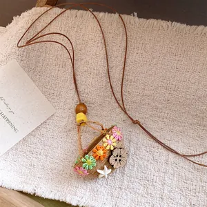 Close-up of a pastoral woven flower basket pendant with colorful floral details and leather cord