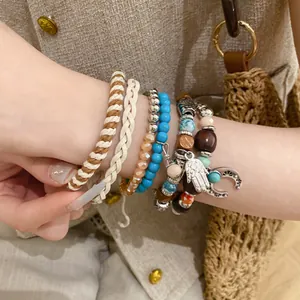 Close-up of bohemian layered bracelets with leather, turquoise beads, and charms.