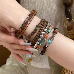 Close-up of bohemian beaded bracelet set featuring wood, leather, and leaf charms
