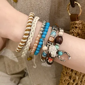 Detail view of bohemian layered bracelets featuring turquoise beads and Hamsa hand charms