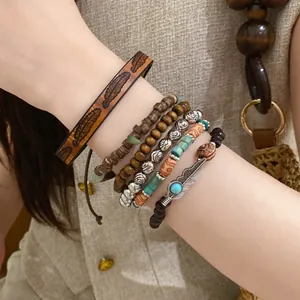 Detail of a bohemian stacked bracelet set with wood beads and leather bands.