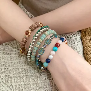 Detail view of stacked bohemian bracelets featuring wood, stone, and coconut shell beads.