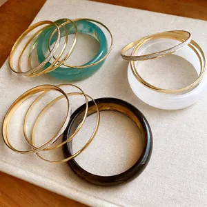 Elegant 5-piece resin and gold metal bangle set featuring glitter and marble textures.