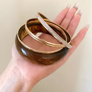 Close-up of resin and gold-tone metal bracelet set showcasing rich amber texture and glitter