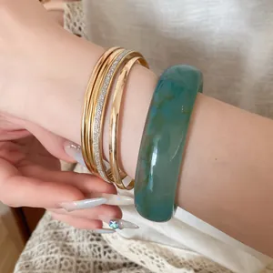Detail view of premium 5-piece bangle set featuring teal resin and gold metal bands