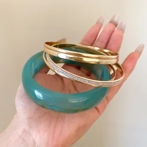 Detailed view of a five-piece set featuring a teal resin bangle and gold metal bracelets.