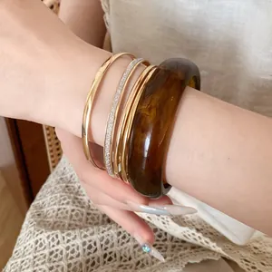 Close-up of a 5-piece jewelry set featuring gold metal and brown resin bangles