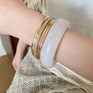 Close-up of elegant 5-piece bracelet set with white resin bangle and gold metal rings