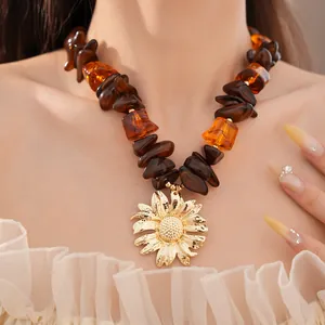 Dettaglio collana in perle di resina ambrata con un grande ciondolo a forma di girasole dorato