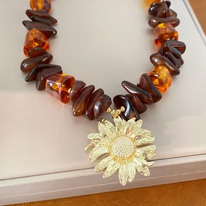 Primo piano di una collana di perle in resina con un grande ciondolo a forma di girasole d'oro