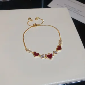 Elegantes vergoldetes Herzarmband mit roten Anhängern und funkelndem Zirkonia-Schmuck.