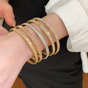 Gedetailleerde weergave van stapelbare dubbele rij stras armbanden in goud, roségoud en zilver.