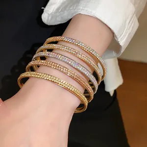Detailopname van elegante dubbelrijige strass-armbanden in goud, zilver en roségoud