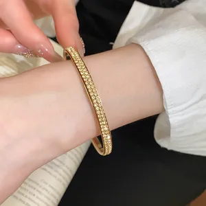 Detail van een luxe goudvergulde armband met twee rijen gele kristallen versiering