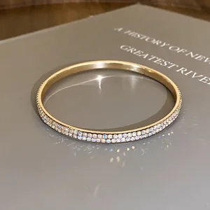 Detailopname van een goudkleurige ronde armband met twee rijen strassteentjes
