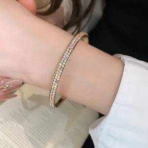 Detailopname van een luxe goudkleurige armband met dubbele rij strass op de vrouwenpols