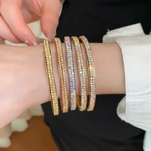 Detailopname van vijf elegante dubbelrijige strass-armringen in goud, zilver en roségoud