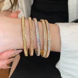 Gedetailleerde close-up van gestapelde dubbelrijige strass-armbanden in goud en zilver op pols