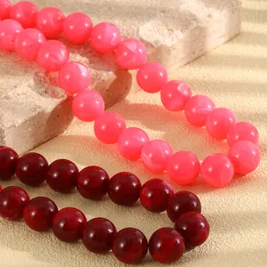 Detaillierte Makroansicht von handgefertigten rosa und dunkelroten Perlenketten auf Stein