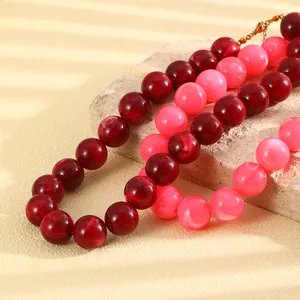 Nahaufnahme von lebhaften rosa und tiefroten marmorierten runden Perlen einer Kette