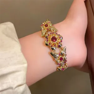 Macro detail of a vintage gold-toned bracelet with red rhinestones and floral motifs