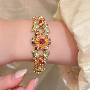 Close-up of a vintage gold-tone flower bracelet with pink rhinestones on a wrist.