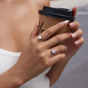 Macro detail of adjustable heart and emerald cut crystal chain rings on a woman's hand