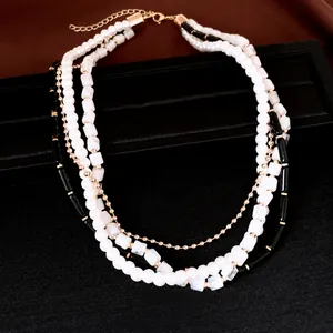 Collier multi-rangs en perles et acrylique avec chaîne élégante dorée.