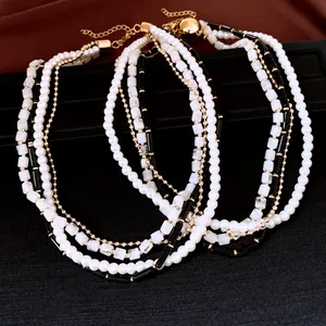 Détail d'un collier multicouche avec des perles blanches et des perles noires géométriques