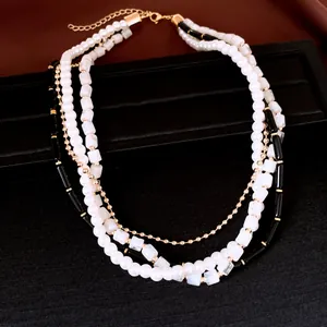Détail d'un collier multicouche avec perles blanches, perles noires et carrées