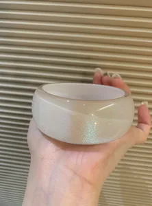 Detail view of a thick pearlescent acrylic bangle featuring a fine iridescent shimmer finish