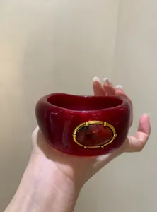 Detailed close-up view of a chunky retro red acrylic bangle with gold-tone frame