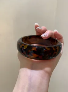 Detailed view of a vintage tortoiseshell pattern acrylic geometric bangle held by hand