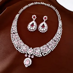 Elegant silver jewelry set with pink teardrop stones and pearls on brown fabric