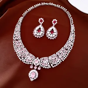 Luxurious silver-tone jewelry set with pink zircons and white pearls on brown silk.