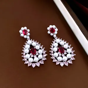 Detailed view of luxury teardrop earrings featuring red crystals, white pearls and pink stones.