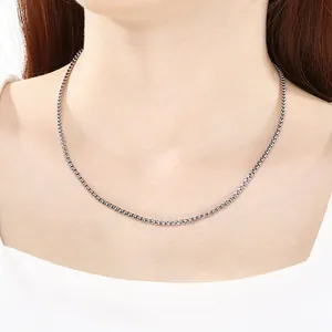 Macro view of a stainless steel box chain necklace with a magnetic clasp on a female neck