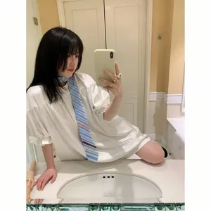 Elegante corbata de seda a rayas azul claro llevada por una modelo en un selfie de espejo.