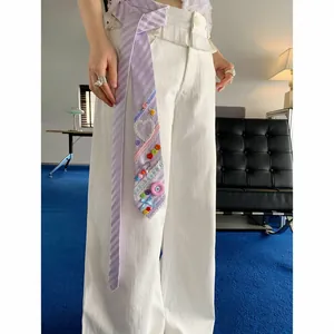Primer plano de una corbata a rayas lavanda con botones de colores y detalles de encaje.