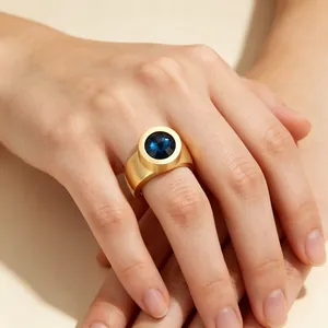 Gros plan d'une bague large mate dorée avec une grande pierre précieuse bleue
