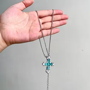 Gros plan détaillé d'un pendentif en forme de croix en zircon vert menthe avec chaîne