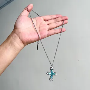 Gros plan détaillé d'un collier en argent avec un pendentif croix en zircon vert menthe