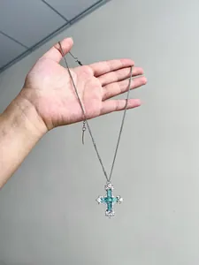 Vue détaillée d'un collier avec pendentif croix en zircon vert menthe et argent.