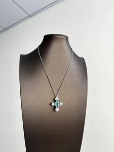 Vue détaillée d'un collier pendentif croix en zircon vert menthe sur un présentoir.