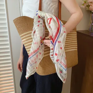 Detail of a floral printed polyester square scarf tied as a decorative bag accessory.