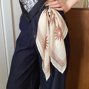 Bohemian cream square bandana with brown sun print tied to a denim jeans belt loop