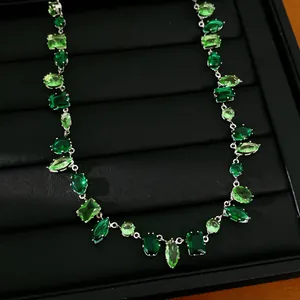 Primer plano de collar de lujo con circonitas verdes y formas geométricas mixtas.