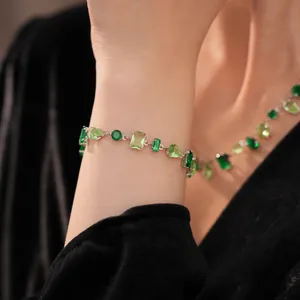 Primer plano de conjunto de pulsera y collar con gemas verdes sobre terciopelo