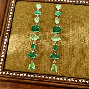 Vista detallada de pendientes largos vintage con piedras geométricas verdes de corte esmeralda