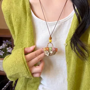 Handmade woven straw bag pendant necklace with colorful flower and starfish on model